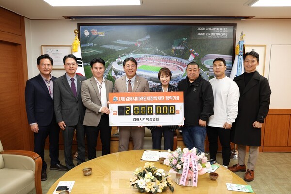 박영애 킥복싱협회장(오른쪽 네 번째)가 홍태용 시장(왼쪽 네 번째)에게 장학금을 전달하고 관계자들과 기념촬영을 하고 있다./사진=김해시
